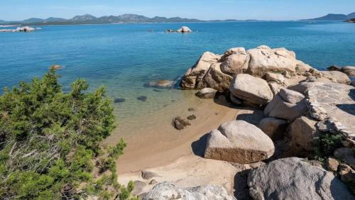 a beach with some rocks and water and trees at Porto Istana's house in Porto Istana