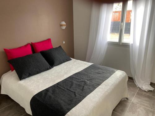 une chambre avec un lit avec des oreillers rouges et noirs dans l'établissement Villa VALLON PONT D'ARC Chemin du Rieusset Salavas classée 3 étoiles, à Salavas