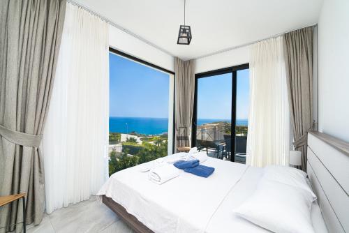 a bedroom with a white bed and large windows at Maldives Holiday Homes in Kérynia