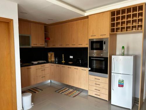 een keuken met houten kasten en een witte koelkast bij Modern Apartment in Praia Baixo - 1 min Walking to Beach in Praia Baixo