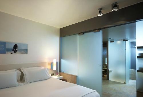 a bedroom with a white bed and a glass wall at Sofitel Munich Bayerpost in Munich
