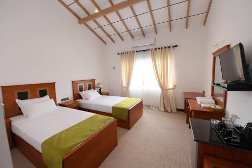 a hotel room with two beds and a television at Seasons Hotel in Kurunegala