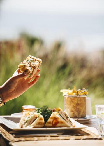 a person holding a slice of pizza next to a plate of food at Paradis Plage Surf Yoga & Spa in Taghazout