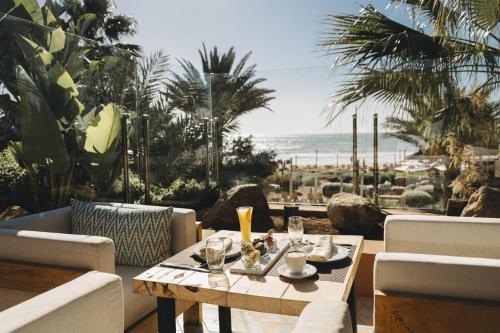 a table on a patio with a view of the beach at Paradis Plage Surf Yoga & Spa in Taghazout