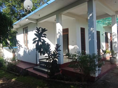 Una casa blanca con un árbol delante. en Summer house resort, en Wellawaya