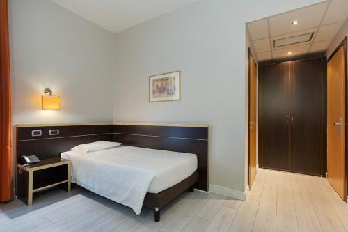 a bedroom with a bed and a table and a door at Hotel Ristorante Al Mulino by LVG Hotel Collection in Alessandria