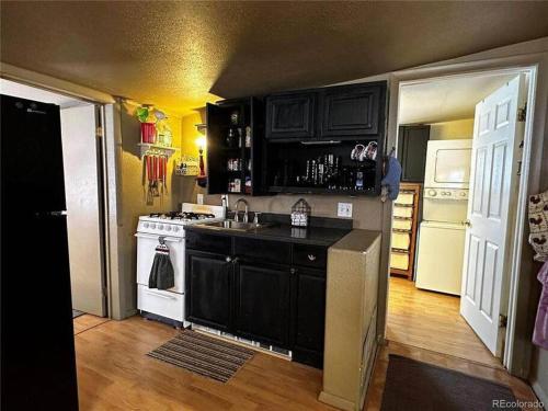 a kitchen with black cabinets and a white stove top oven at The Air Capitol Cottage in Leadville