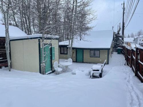 een met sneeuw bedekte tuin met een huis en stoelen bij The Air Capitol Cottage in Leadville