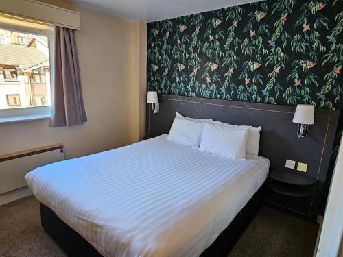 a bedroom with a large bed with a floral wall at Pendulum Hotel in Manchester