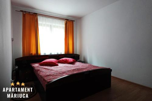 a bedroom with a bed with red sheets and a window at Mariuca Apartament in Buşteni