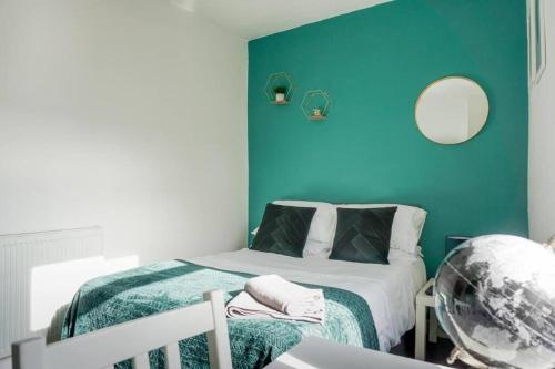 a bedroom with a bed and a blue wall at Charming 3-Bedroom Retreat in Barrow-in-Furness by Amazing Spaces Relocations Ltd. in Barrow in Furness