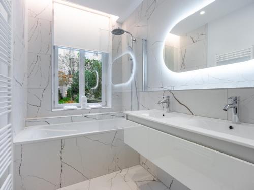 a white bathroom with two sinks and a mirror at La Suite des Cordeliers - Résidence d'Exception in Nancy