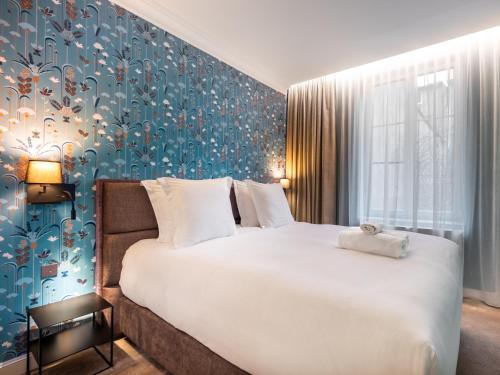 une chambre avec un grand lit et un mur bleu dans l'établissement La Suite des Cordeliers - Résidence d'Exception, à Nancy