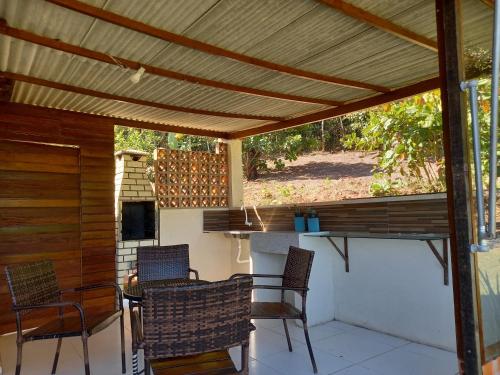 um pátio com uma pérgola de madeira com cadeiras e uma mesa em CASA DA SERRA na Chácara Paraíso em Bananeiras