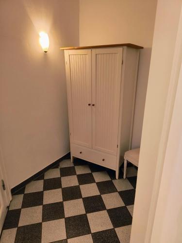 a room with a cabinet and a checkered floor at Gutshaus Krimvitz Kleines Doppelzimmer inkl Frühstück in Putbus