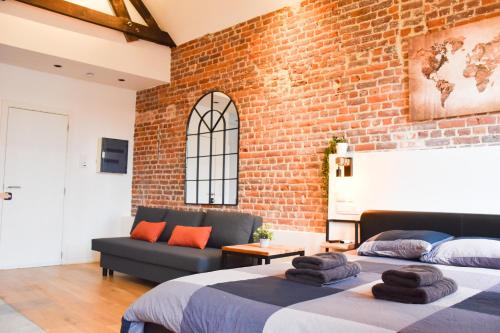 two beds in a room with a brick wall at Fontainas Apartments in Brussels