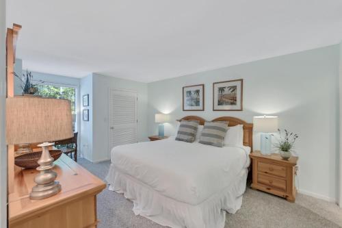 ein Schlafzimmer mit einem weißen Bett und einem Tisch mit einer Lampe in der Unterkunft 1357 Pelican Watch in Seabrook Island