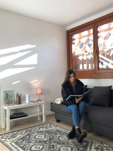 a woman sitting on a couch reading a book at Mountain Suite in Raveo