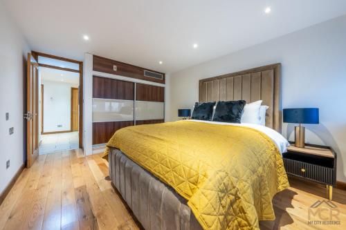 um quarto com uma cama grande e um cobertor amarelo em The George Street Residences em Londres