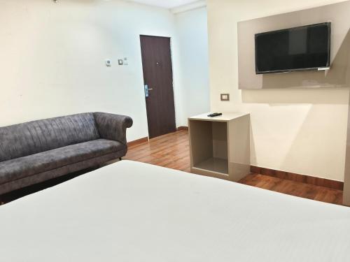 a room with a bed and a couch and a television at Hotel Sharma Regency in Lucknow