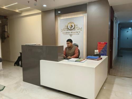 a man sitting at a counter in a lobby at Hotel Sharma Regency in Lucknow