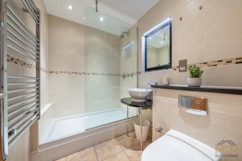 a bathroom with a tub and a sink and a toilet at The George Street Residences in London