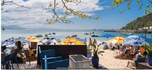 a group of people on a beach with umbrellas at Pousada Sabores do Mar Laranjeiras in Balneário Camboriú