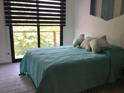 Cama verde en habitación con ventana en Villa Constantino en Telchac Puerto