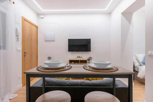 ein Wohnzimmer mit einem Tisch mit zwei Gerichten darauf in der Unterkunft Ponzano Foodie Encanto Madrileño in Madrid