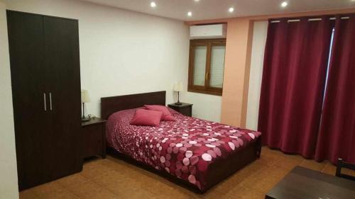 1 dormitorio con 1 cama con edredón rojo en Apartamenticos Boggiero I, en Zaragoza