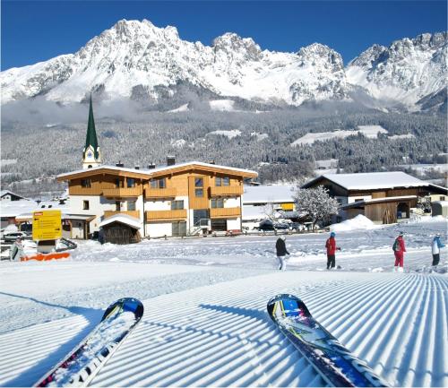 a group of skis in the snow in front of a lodge at Kaiserapart Steinadler - ELLMAU Zentrum in Ellmau