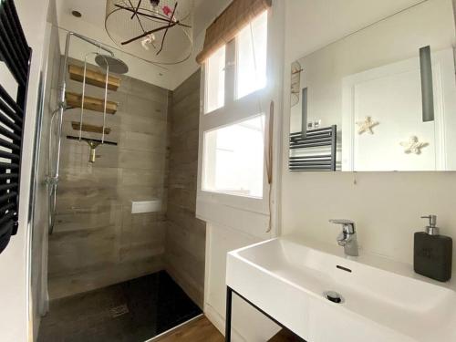 La salle de bains blanche est pourvue d'un lavabo et d'une douche. dans l'établissement Villa familiale à Arcachon plage, à Arcachon