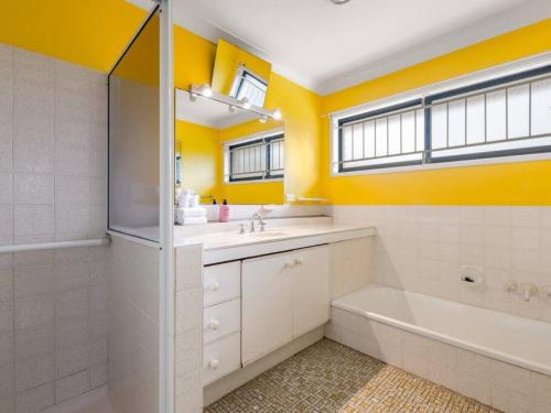 a bathroom with yellow walls and a tub and a sink at 5Mins walk to mall 4BR Family home nicely located in Brisbane