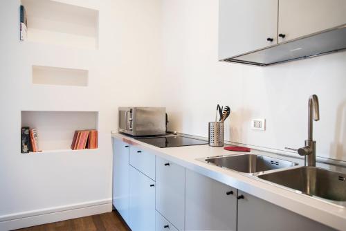 una cucina con armadi bianchi e lavandino di Vittore Rooms & Apartment a Milano