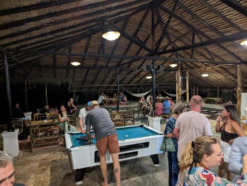 a group of people standing around a pool table at The River Retreat Koh Mak in Ko Mak