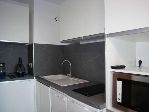 une cuisine blanche avec un évier et un micro-ondes dans l'établissement Studio skis aux pieds pour 4 personnes, cœur de station - FR-1-322-14, aux Orres