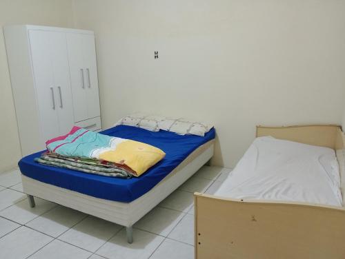 um pequeno quarto com uma cama com lençóis azuis em Casa Imbé 100 MT do Mar em Imbé