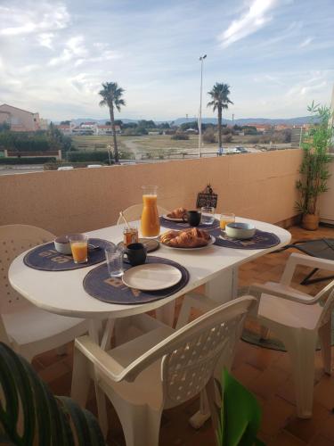una mesa con 2 platos de comida en el balcón en Studio 200m de la plage Le Barcares, en Le Barcarès