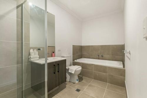 uma casa de banho com uma banheira, um WC e um chuveiro em 3BR home with cozy interior design em Browns Plains