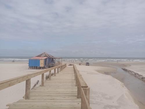 a wooden pier with a building on the beach at Casa Imbé 100 MT do Mar in Imbé