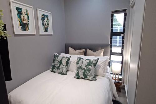 a bedroom with a white bed with pillows and a window at Tiny Home on Broadway in Gqeberha