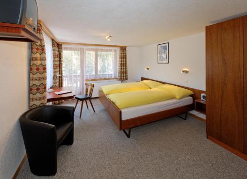 a bedroom with a yellow bed and a chair at Hotel zum See in Grächen