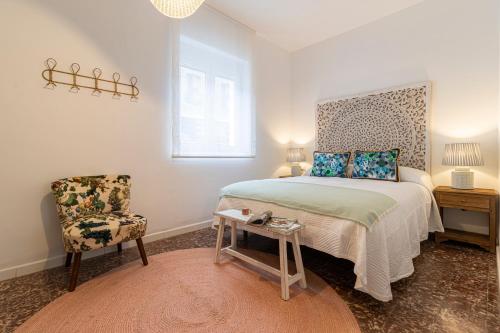 1 dormitorio con 1 cama y 1 silla en El Balcón de la Bodega - Luxurious apartment in Jerez with gym en Jerez de la Frontera