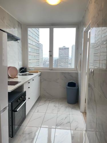 - une cuisine blanche avec une grande fenêtre et un évier dans l'établissement SCI IMMO PARIS PORTE DE CHOISY, à Paris