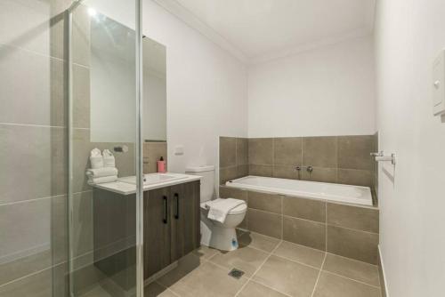 a bathroom with a tub and a toilet and a shower at Dual key 5BR Family home with stunning interior in Browns Plains