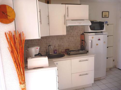 マルセイヤンにあるAppartement Marseillan-Plage, 2 pièces, 4 personnes - FR-1-387-70の白いキャビネット、シンク、冷蔵庫付きのキッチンが備わります。