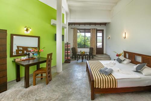 a bedroom with a bed and a desk and a table at VillaWatuna in Unawatuna