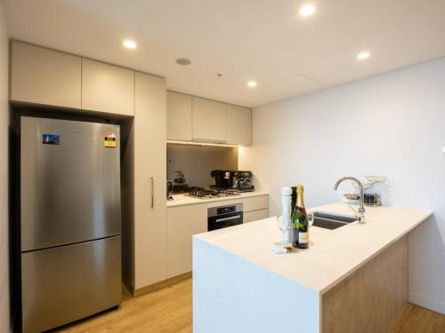 una cocina con nevera de acero inoxidable y armarios blancos en Stunning River views 2BR city centre Apt en Brisbane