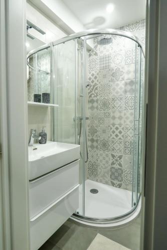 a white bathroom with a shower and a sink at Apartman Cesarac in Osijek