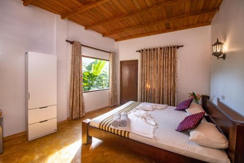 a bedroom with a bed and a large window at VillaWatuna in Unawatuna